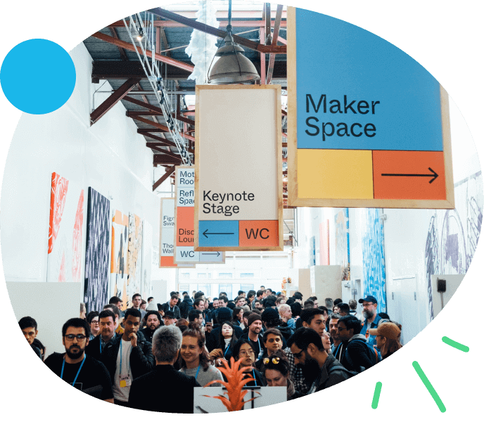 Crowded corridor in an event venue with overhead signs pointing to Maker Space and Keynote Stage.