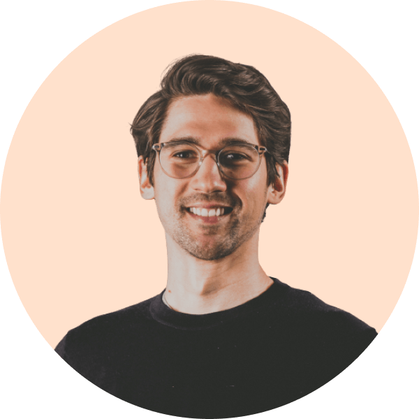 Portrait of a smiling young man with glasses and dark hair against an orange circular background.