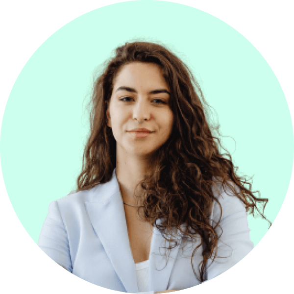 Woman with long curly brown hair wearing a light blue blazer against a bright green circular background.