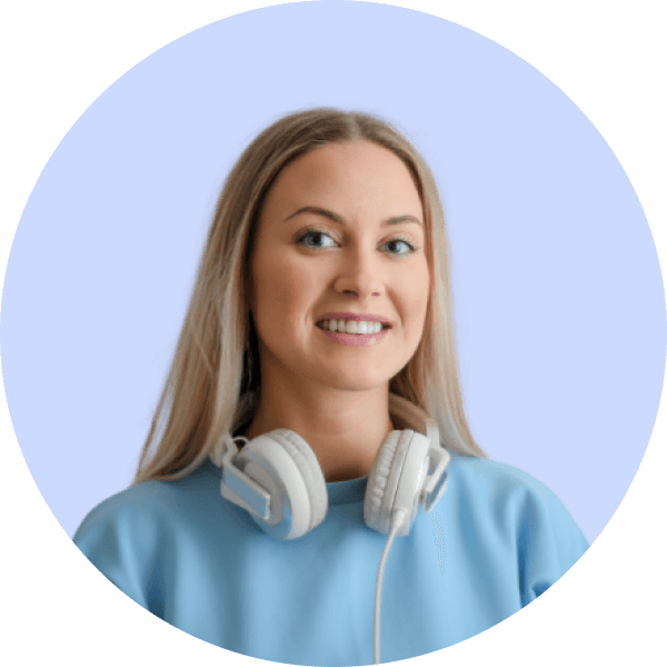 Smiling young woman with long blonde hair wearing a light blue sweatshirt and white headphones around her neck against a blue background.