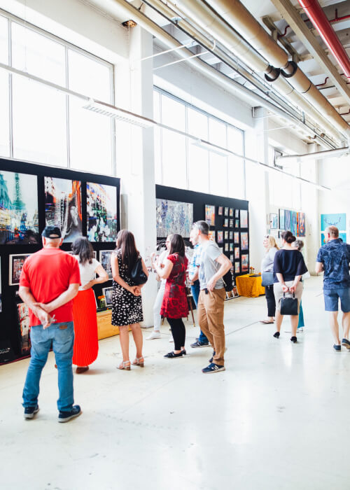 group of people watching some painting or art hanging on wall.
