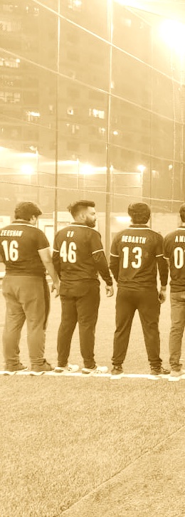 Four men standing in a line on a grass field at night wearing matching sports jerseys with numbers and names on the back.
