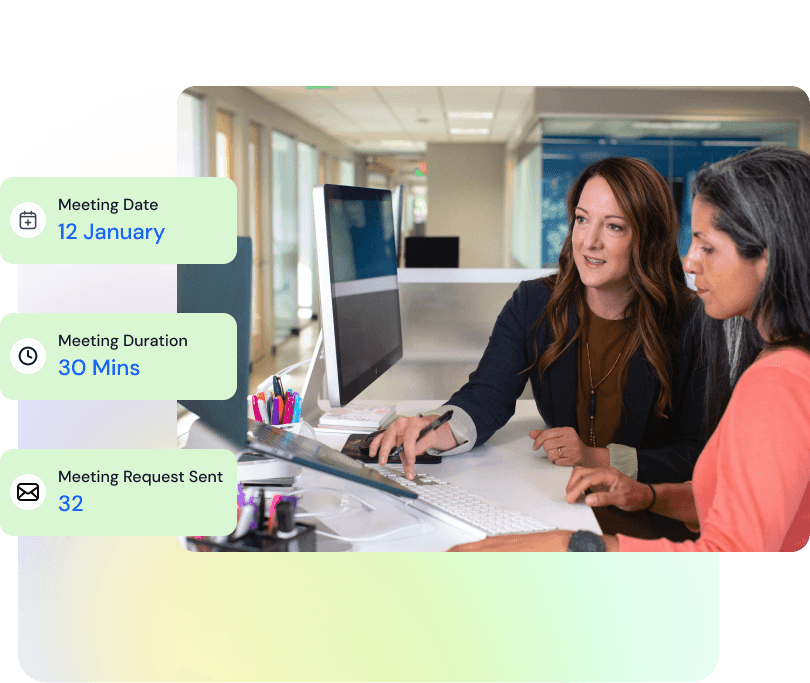 Two women discussing work at an office desk with a computer, accompanied by meeting details: date 12 January, duration 30 minutes, and 32 meeting requests sent.